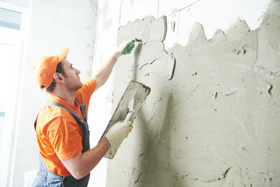man putting cement to the wall